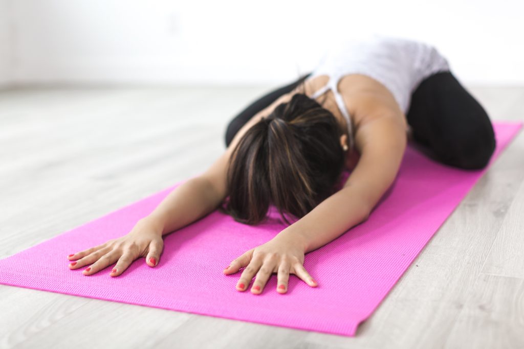 Woman doing yoga pose on pink yoga mat